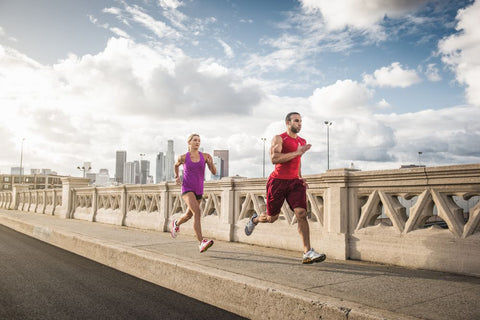 Two runners on a bridge with a city skyline in the background