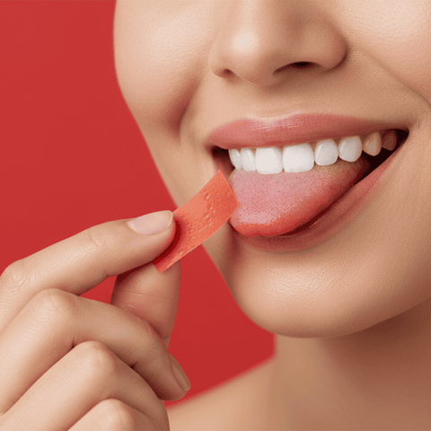 Person holding a L-arginine oral strip with a red background

